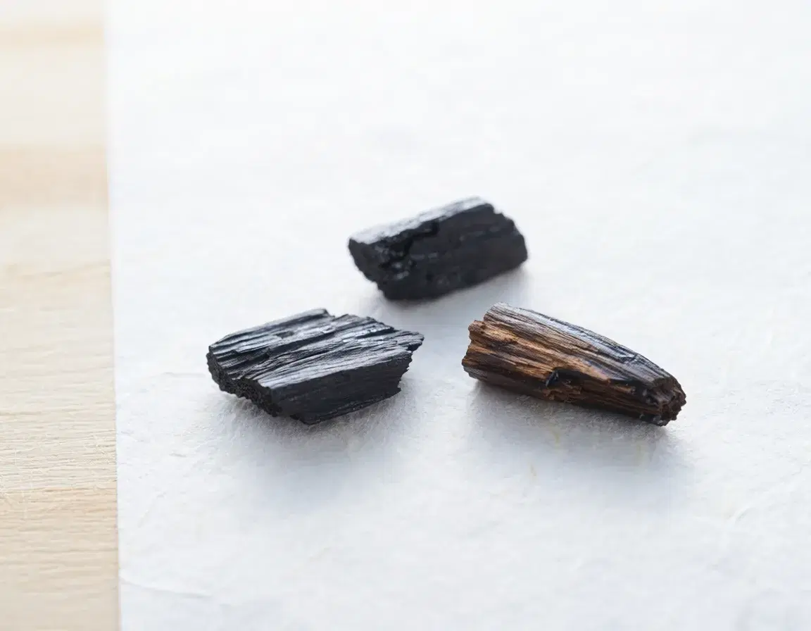 黒く艶のある沈香の小片が三片、白い和紙の上に置かれている